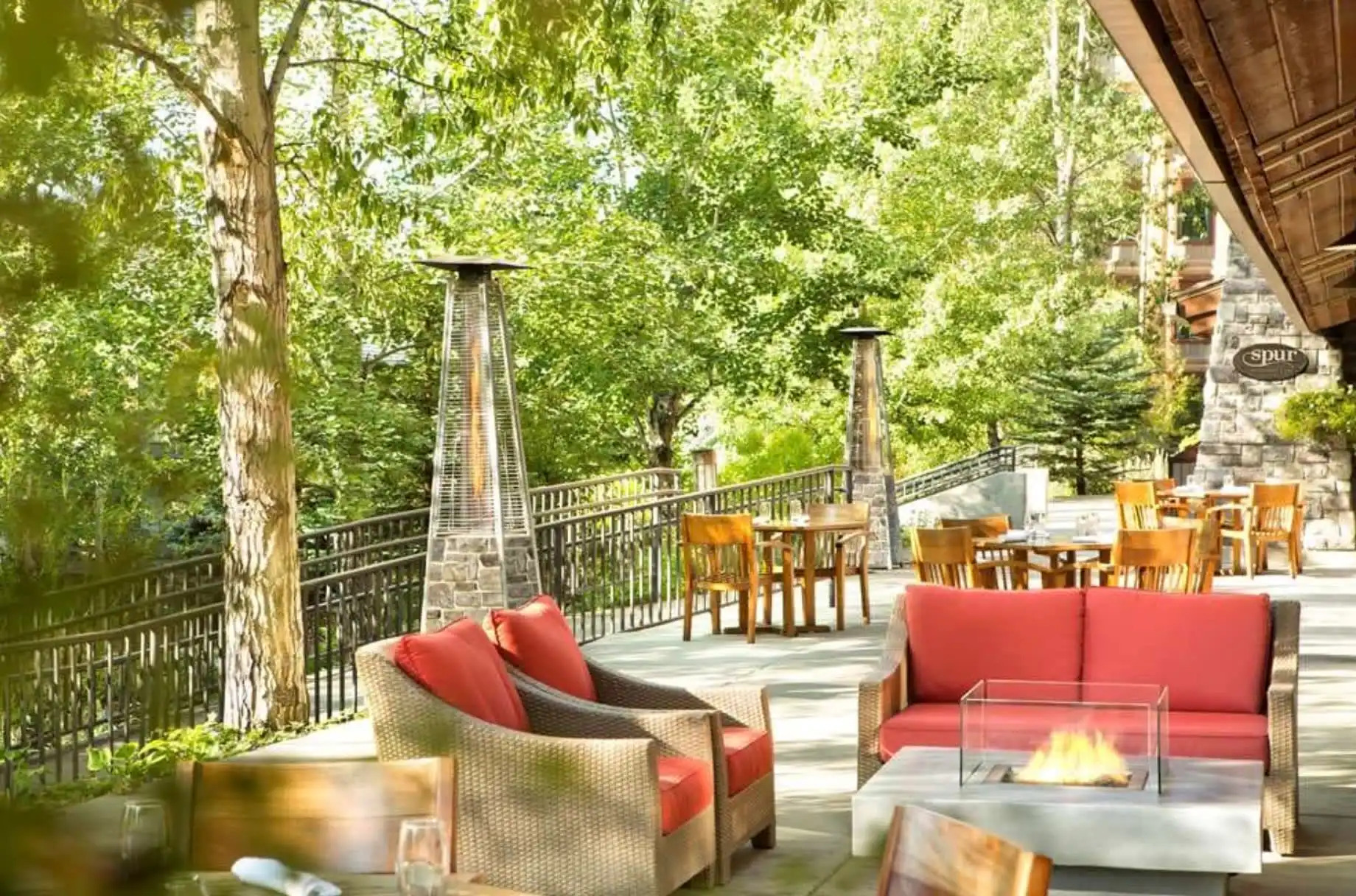 Shaded patio with red and wicker seating and fire pit